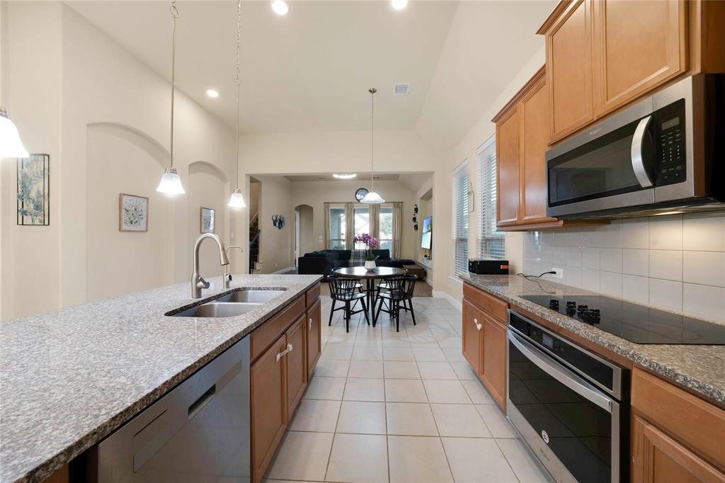 7024 Green Field Street Little Elm, TX 76227 - Photo 5 of 27 a kitchen with stainless steel appliances granite countertop a stove a sink and a microwave