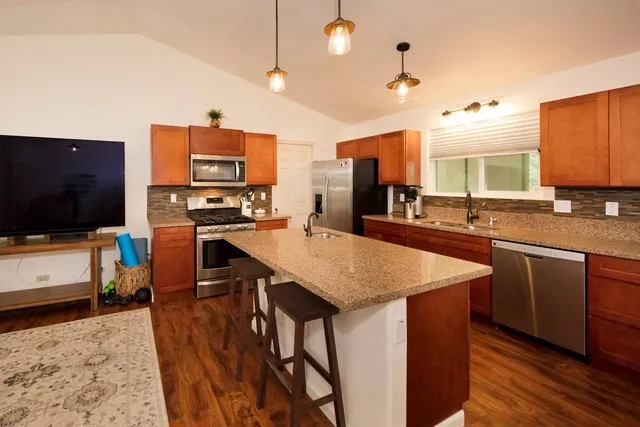 a kitchen with stainless steel appliances kitchen island granite countertop a sink a stove and a microwave