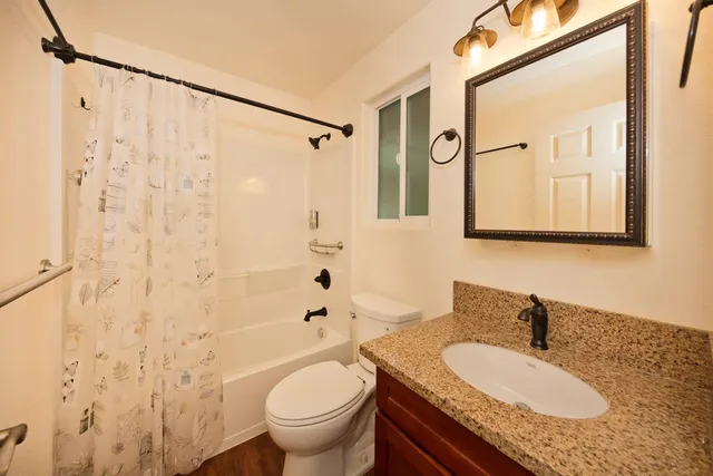 a bathroom with a granite countertop sink a toilet and a mirror
