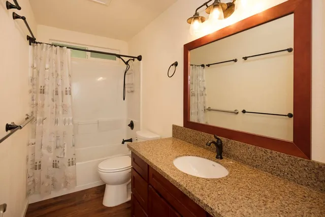 a bathroom with a granite countertop sink toilet a mirror and shower
