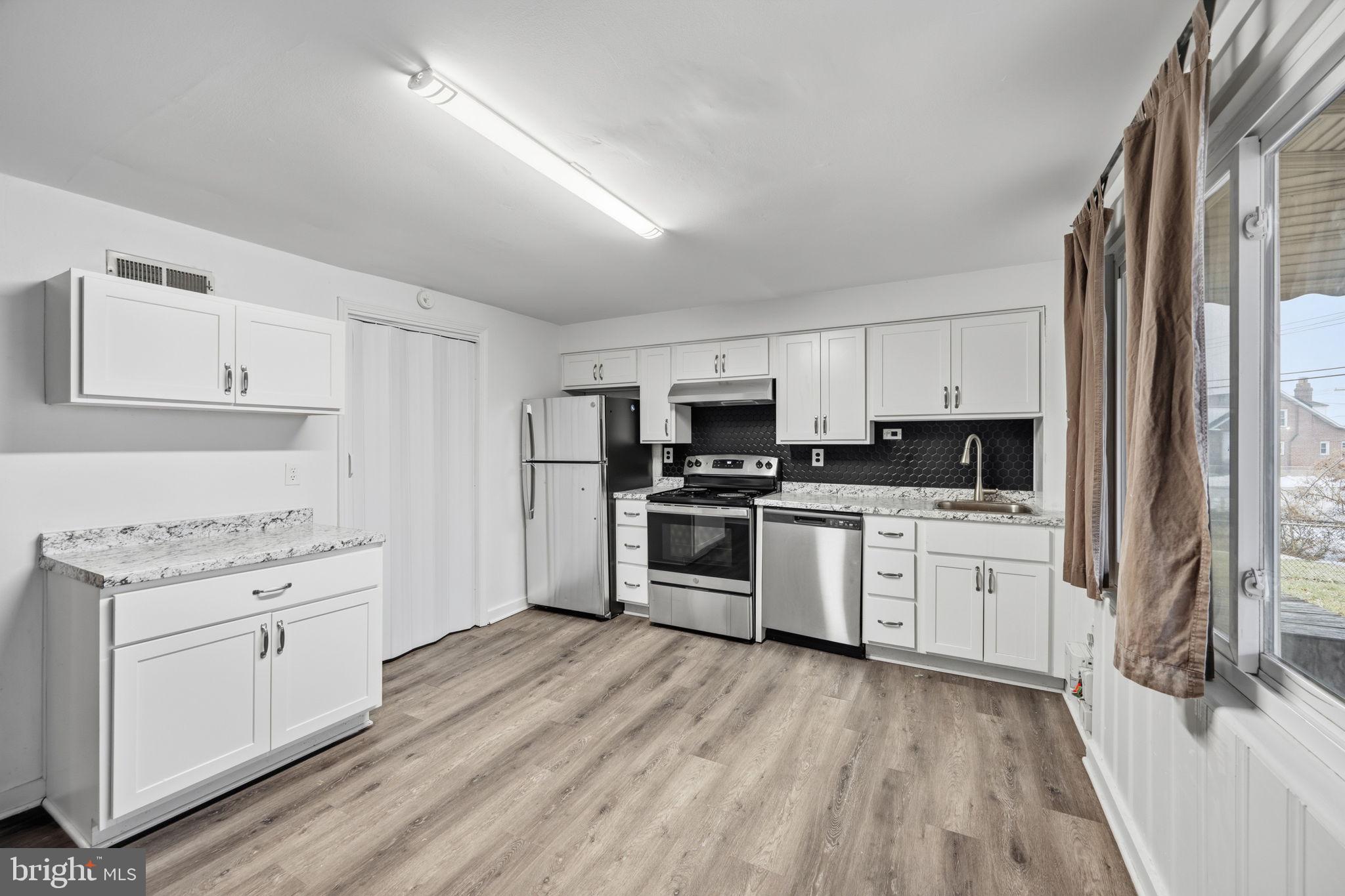 7911 Bank Street Baltimore, MD 21224 - Photo 12 of 40 a kitchen with granite countertop white cabinets and stainless steel appliances