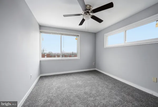 an empty room with a window and a fan