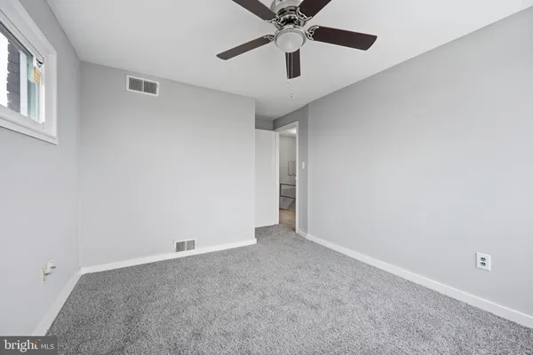 an empty room with a window and a fan
