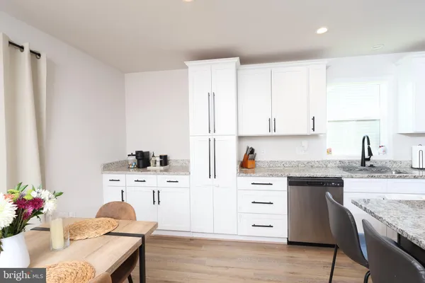 a kitchen with granite countertop a sink stainless steel appliances and white cabinets