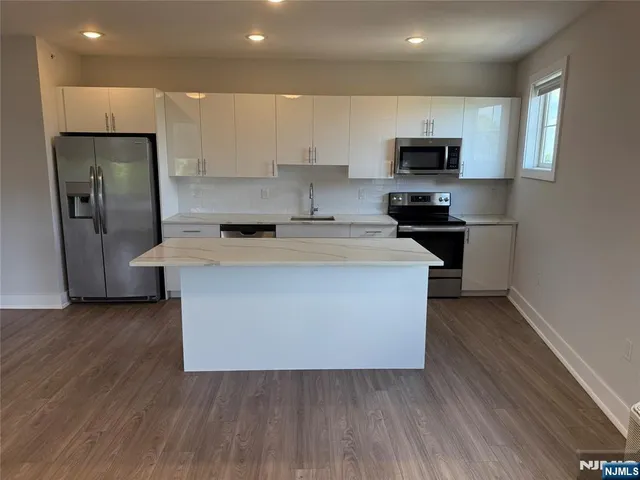 a kitchen with stainless steel appliances a microwave a stove a sink and a refrigerator