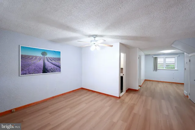 a view of a big room with wooden floor and chandelier fan