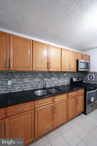 a kitchen with granite countertop stainless steel appliances white cabinets sink and window