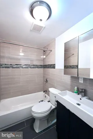 a bathroom with a double vanity sink toilet mirror and bathtub