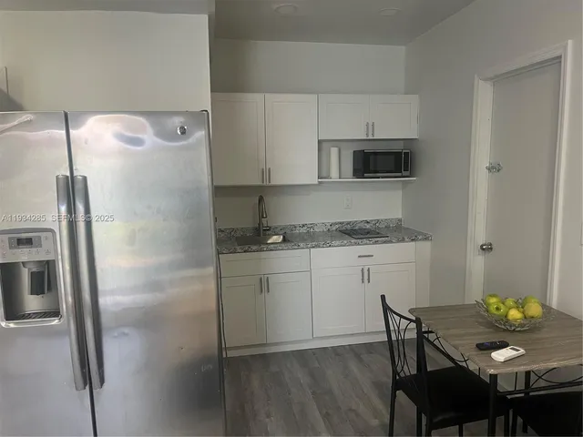a kitchen with a refrigerator and wooden floor