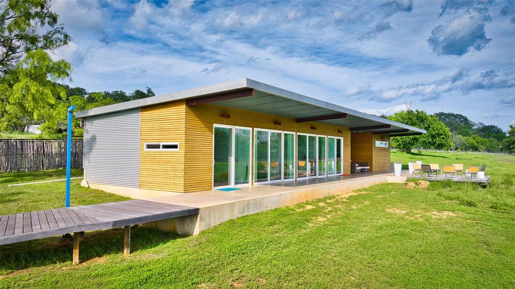 2969 County Lane Talpa, TX 76882 - Photo 27 of 40 Contemporary exterior with a low-slope roofline, featuring horizontal wood siding and corrugated metal paneling