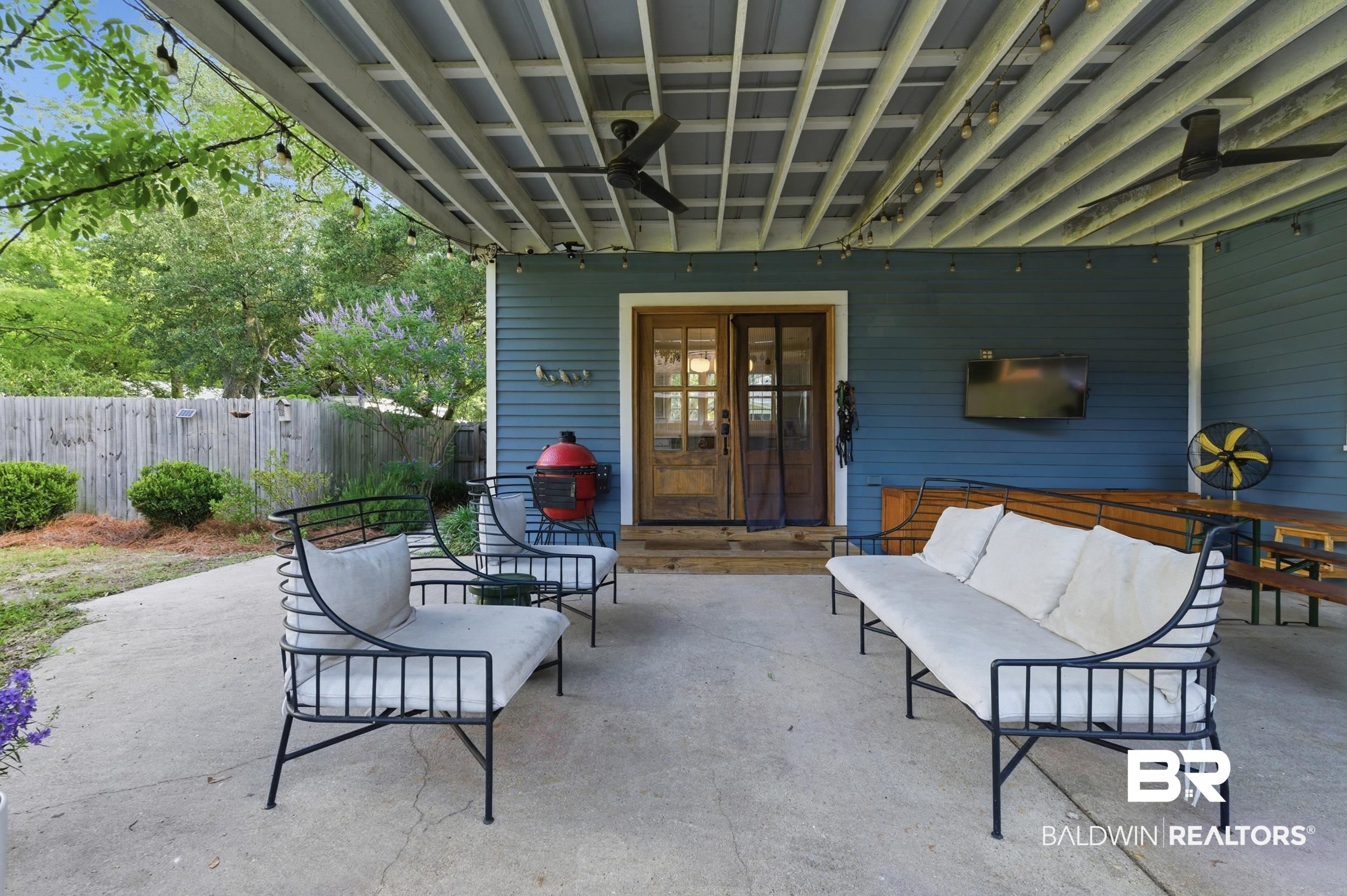 350 Charles Street Mobile, AL 36604 - Photo 31 of 52 Spacious covered patio featuring concrete flooring, a paneled ceiling with dual ceiling fans, string lighting, and direct access through glass-paned double doors