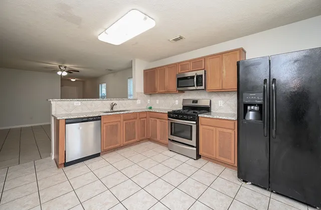 a kitchen with stainless steel appliances granite countertop a refrigerator stove top oven and sink