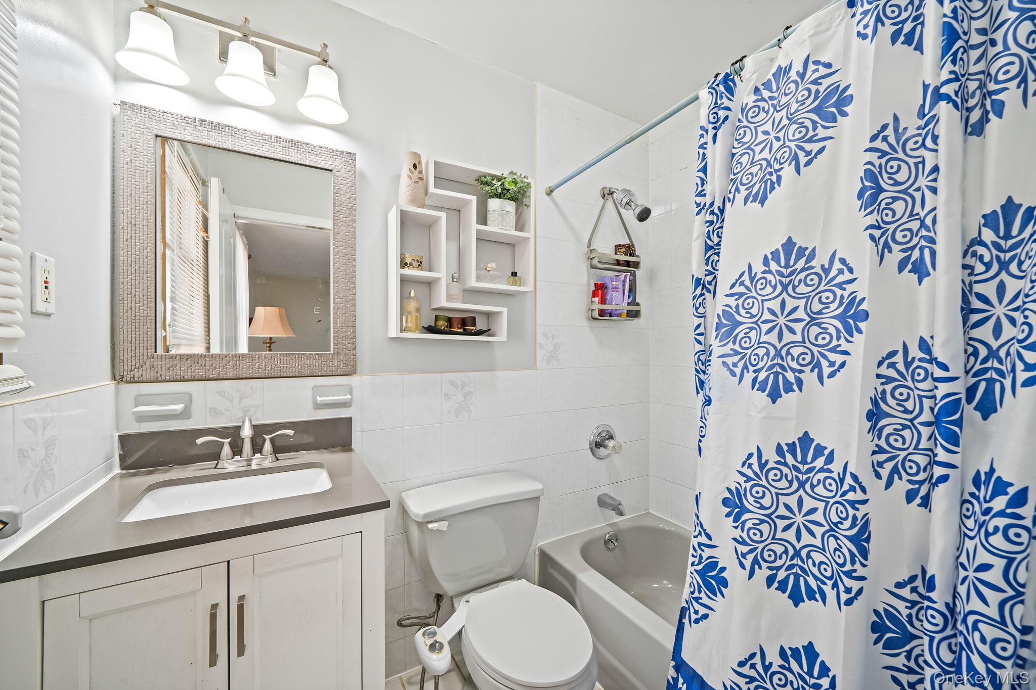 84-70 159th Street Queens, NY 11432 - Photo 23 of 50 Bathroom with vanity, shower / bath combo with shower curtain, tile walls, and a wainscoted wall