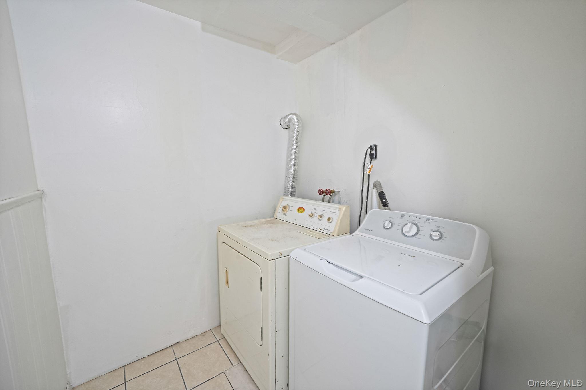 84-70 159th Street Queens, NY 11432 - Photo 31 of 50 Laundry room with washing machine and dryer and light tile patterned flooring