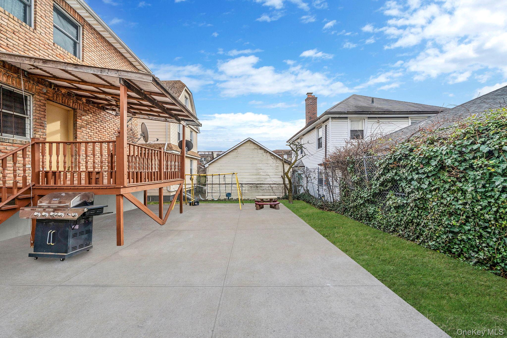 84-70 159th Street Queens, NY 11432 - Photo 36 of 50 Fenced backyard with grilling area, a wooden deck, and a fire pit