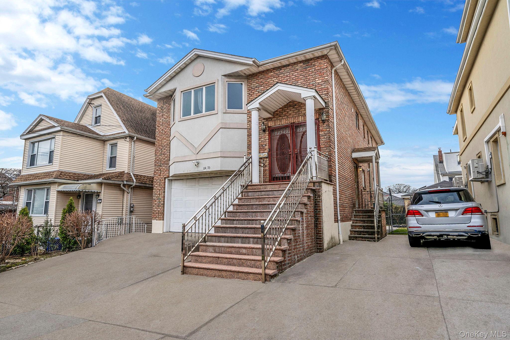 84-70 159th Street Queens, NY 11432 - Photo 40 of 50 View of front of home featuring brick siding, concrete driveway, and a garage