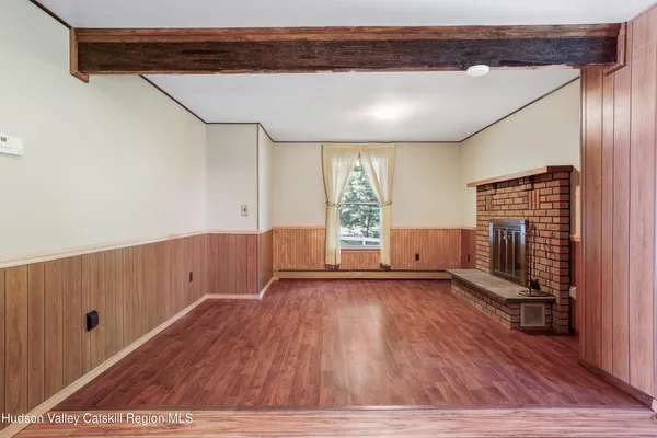 a view of an empty room with a fireplace and wooden floor