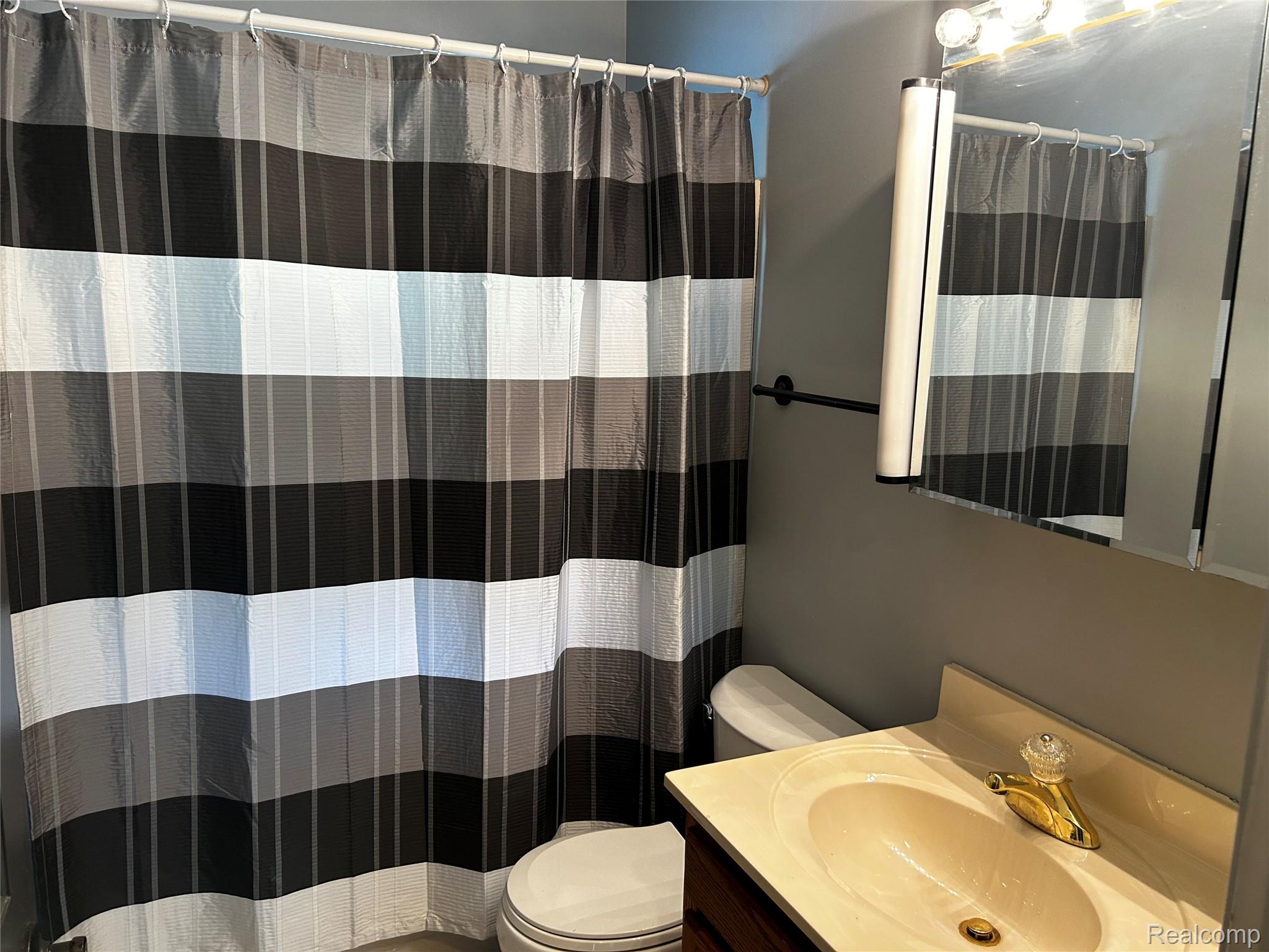 5440 Deland Road Flushing, MI 48433 - Photo 10 of 25 Bathroom vanity with a built-in sink, gold-finish faucet, and a large wall-mounted mirror.