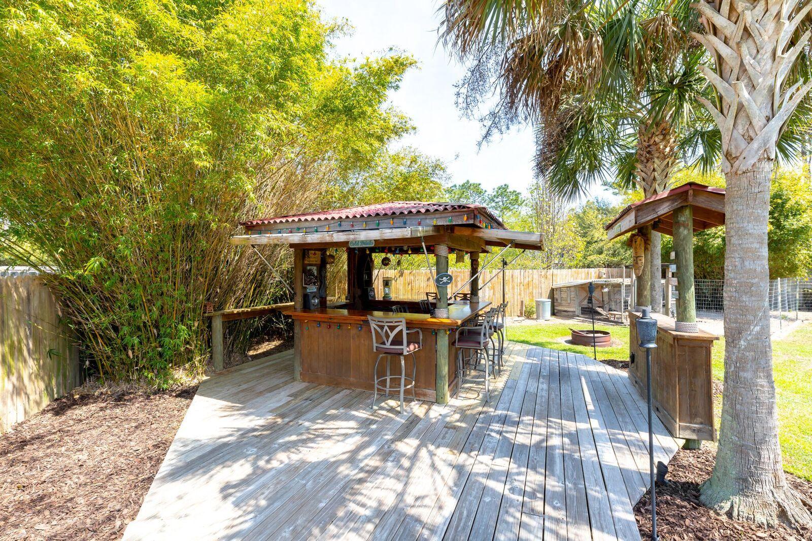 7780 Fenwick Street Navarre, FL 32566 - Photo 27 of 31 a view of a patio with table and chairs under an umbrella with large trees