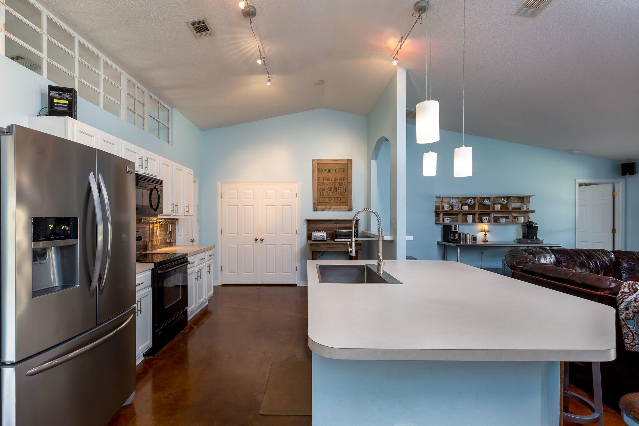7780 Fenwick Street Navarre, FL 32566 - Photo 7 of 31 a large kitchen with a refrigerator a sink a stove and cabinets