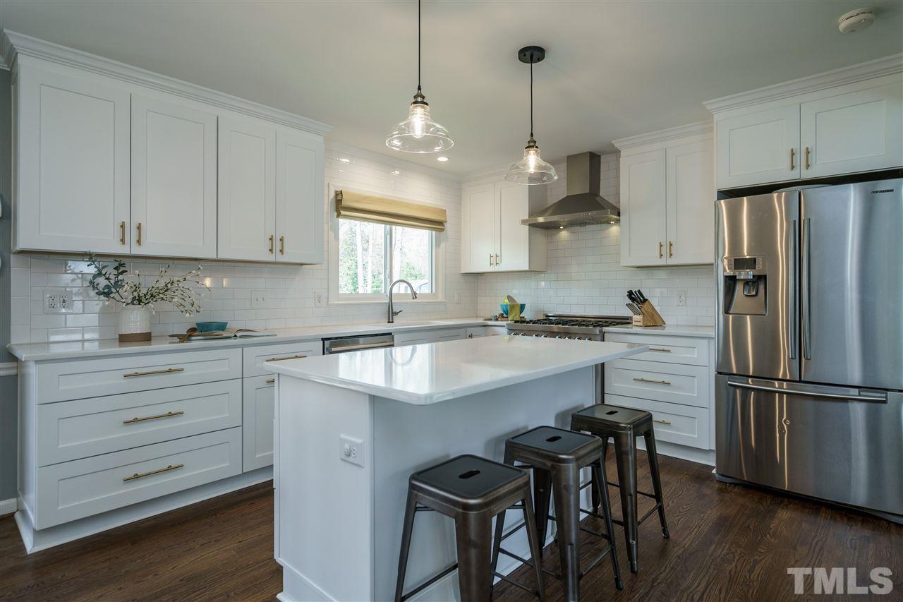 419 East Rowan Street Raleigh, NC 27609 - Photo 10 of 30 a kitchen with stainless steel appliances granite countertop a sink a stove a refrigerator and island with wooden floor