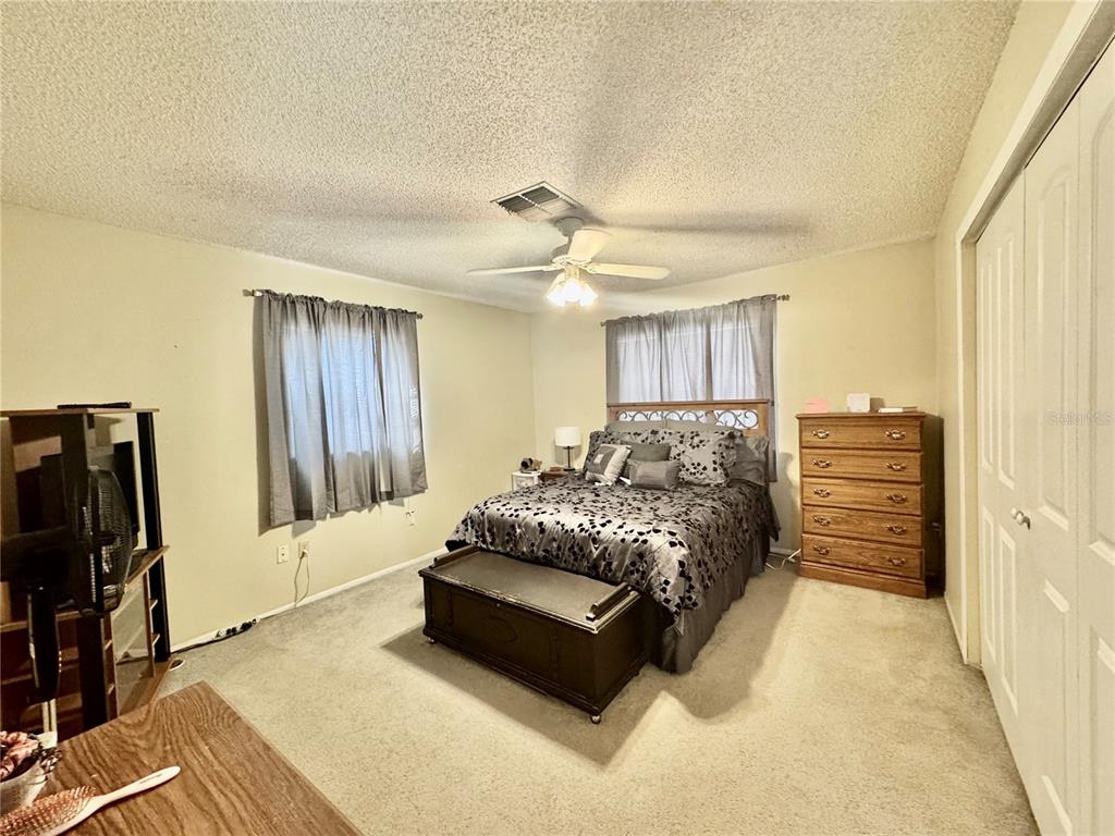 13188 Delbarton Street Spring Hill, FL 34609 - Photo 12 of 23 a spacious bedroom with a bed and a walk in closet