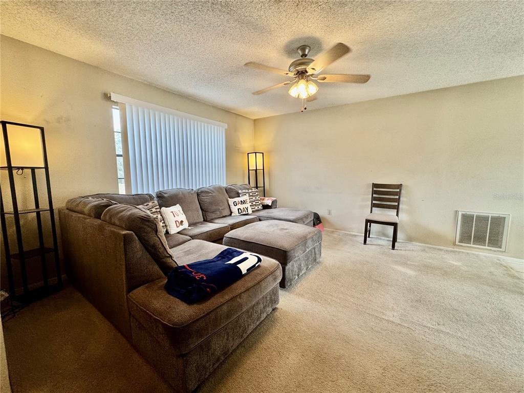 13188 Delbarton Street Spring Hill, FL 34609 - Photo 4 of 23 a living room with furniture and a ceiling fan