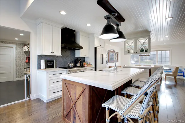 a kitchen with stainless steel appliances granite countertop a stove a sink a microwave a dining table and chairs with wooden floor