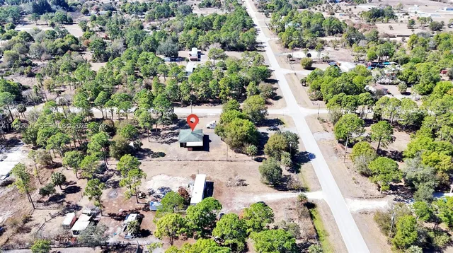 an aerial view of residential house with outdoor space and trees all around