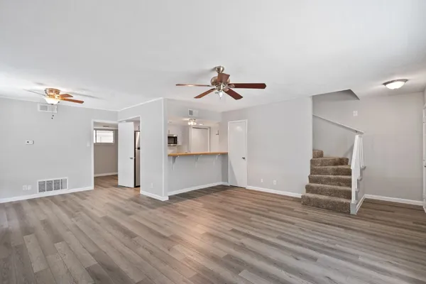 a view of empty room with wooden floor and ceiling fan