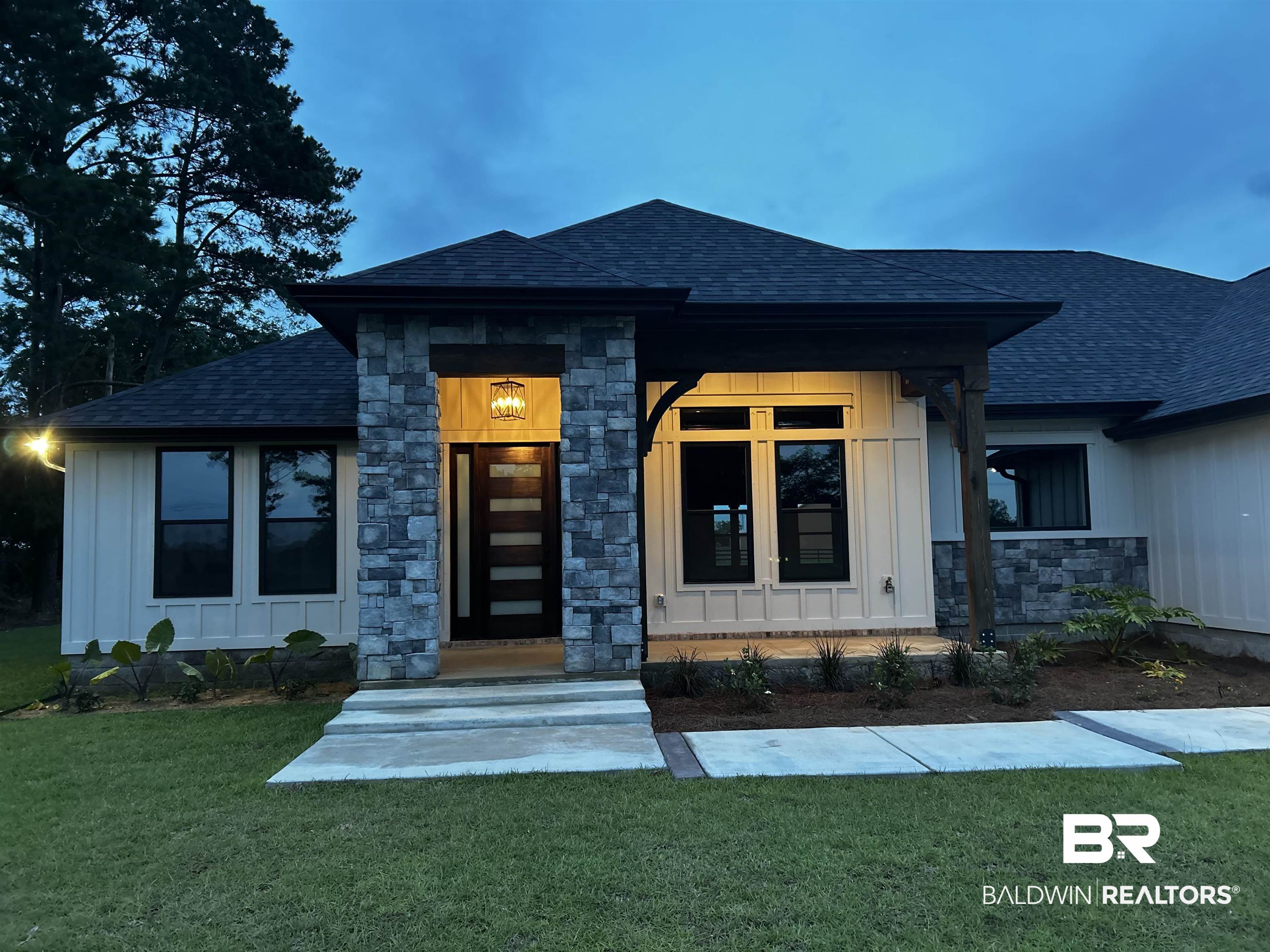 13066 Gopher Court Elberta, AL 36530 - Photo 32 of 38 Contemporary exterior featuring stacked stone accents, dark-framed windows, a prominent entryway with modern door, board and batten siding, and a dark shingle roof