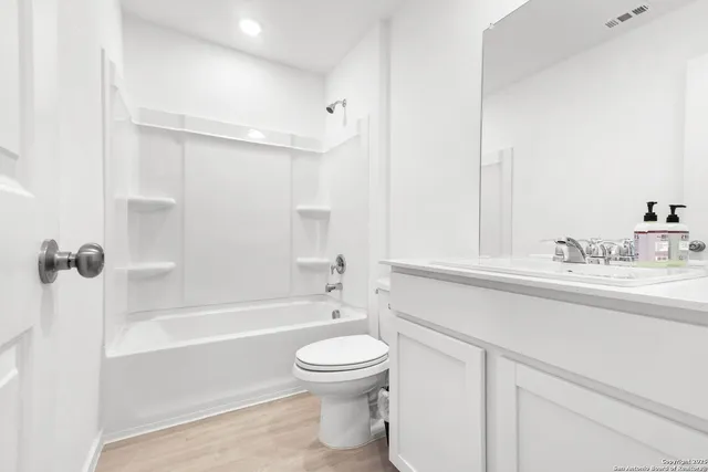 a bathroom with a bathtub shower sink vanity mirror and toilet