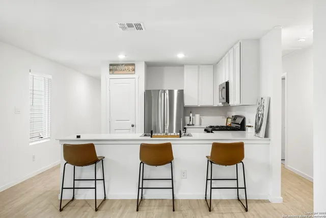 a kitchen with stainless steel appliances granite countertop a stove a refrigerator a kitchen island and chairs in it