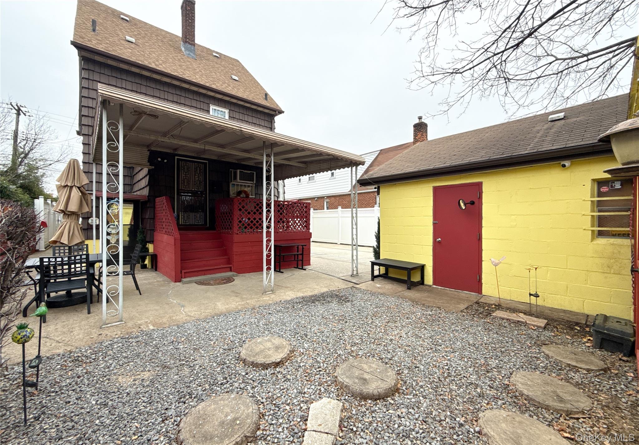 134-37 58th Road Queens, NY 11355 - Photo 7 of 24 Back of property featuring a chimney, a patio area, and roof with shingles