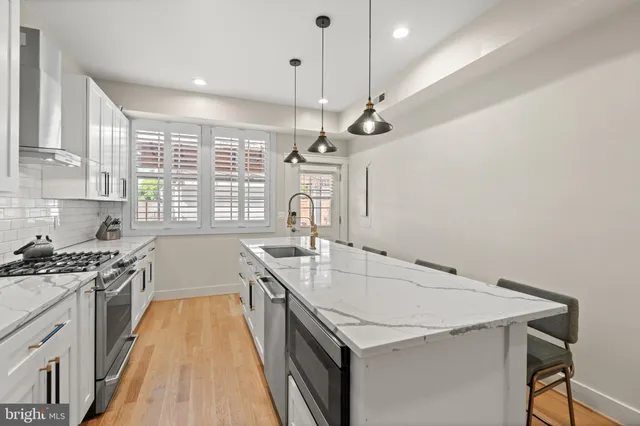 a kitchen with a stove a sink a window and chairs