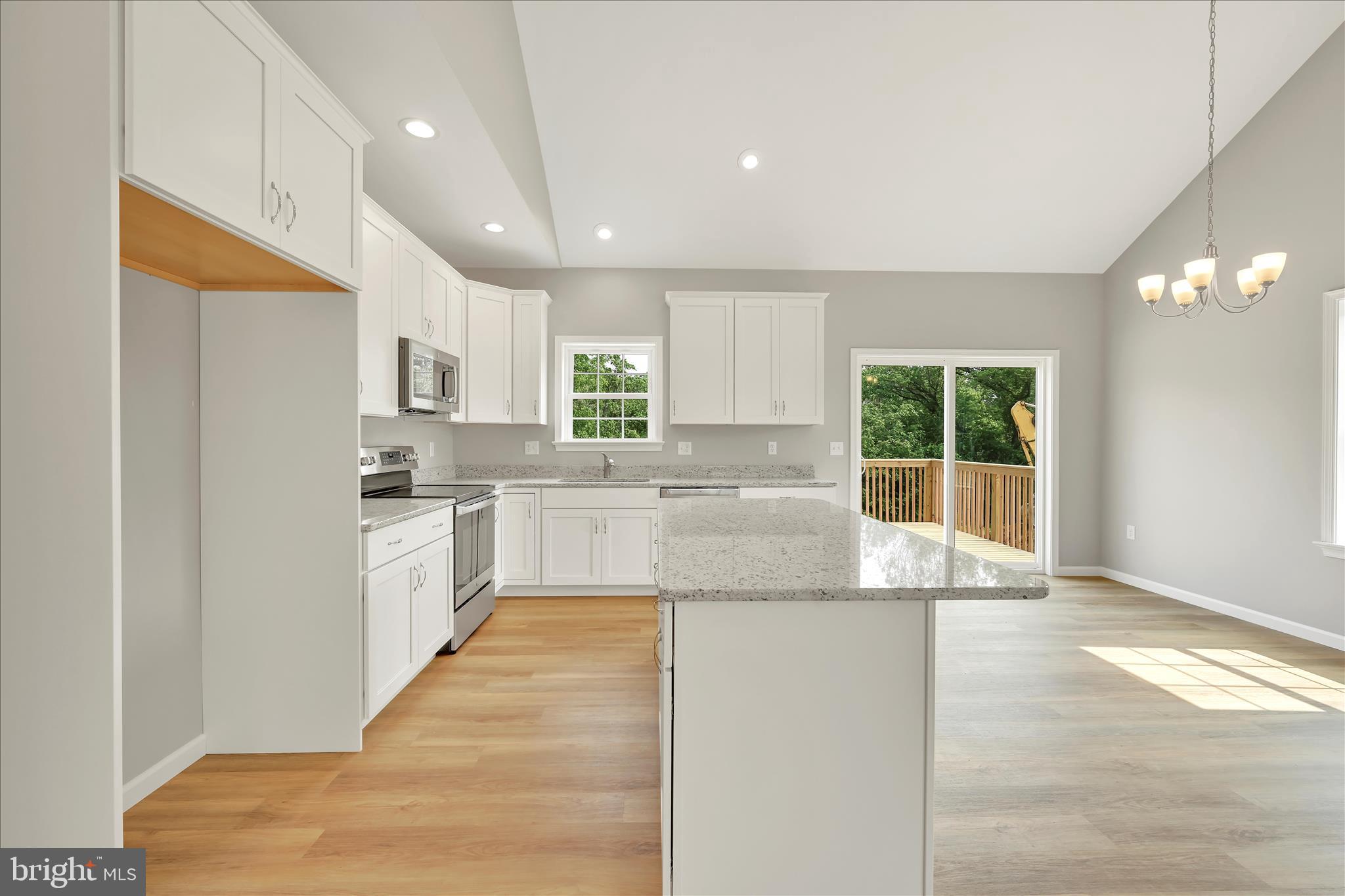 227 Pilgrim Drive Lancaster, PA 17603 - Photo 7 of 24 a large kitchen with kitchen island a stove a sink a refrigerator and white cabinets with wooden floor