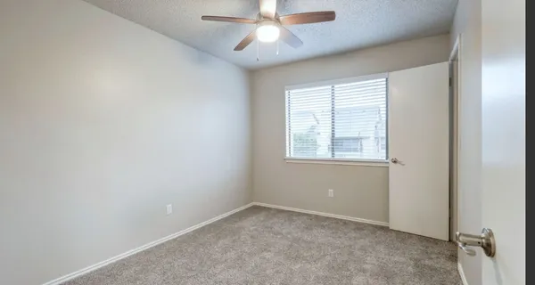 an empty room with a window and a fan