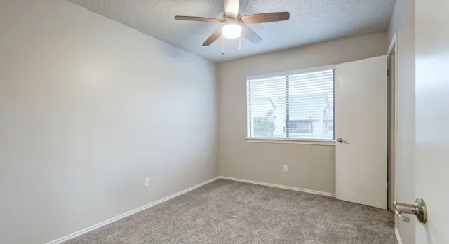 an empty room with a window and a fan
