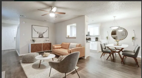 a living room with furniture a table and kitchen view