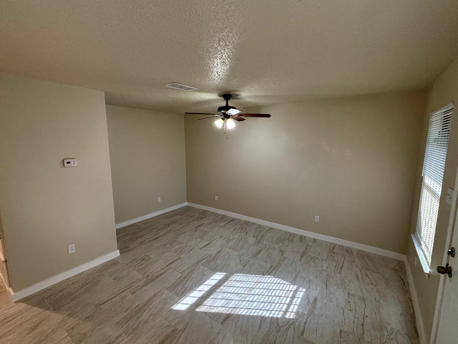 Textured tile flooring runs throughout this versatile living area with neutral walls.