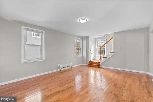 a view of empty room with wooden floor and window