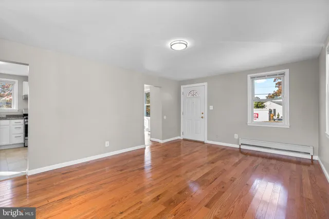an empty room with wooden floor and windows