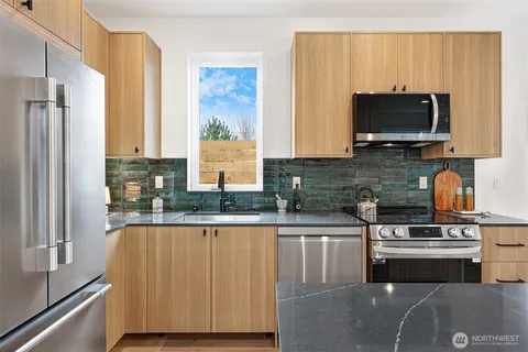 a kitchen with stainless steel appliances granite countertop a stove a sink and a microwave