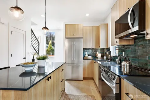 a kitchen with stainless steel appliances granite countertop a sink a stove and a wooden floors
