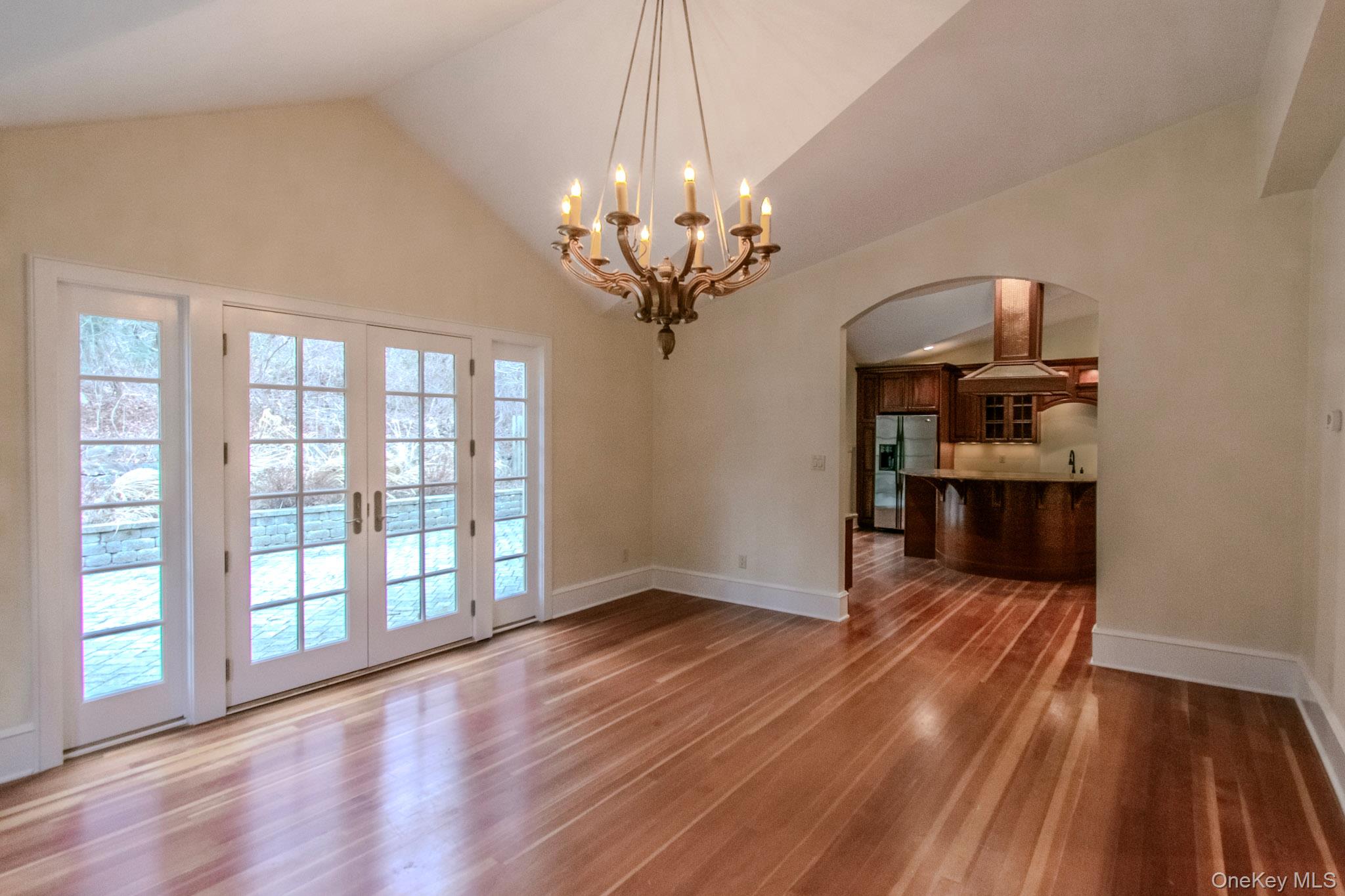 54 East Lake Stable Road Tuxedo Park, NY 10987 - Photo 11 of 31 Unfurnished dining area featuring hardwood / wood-style floors, high vaulted ceiling, french doors, and an inviting chandelier