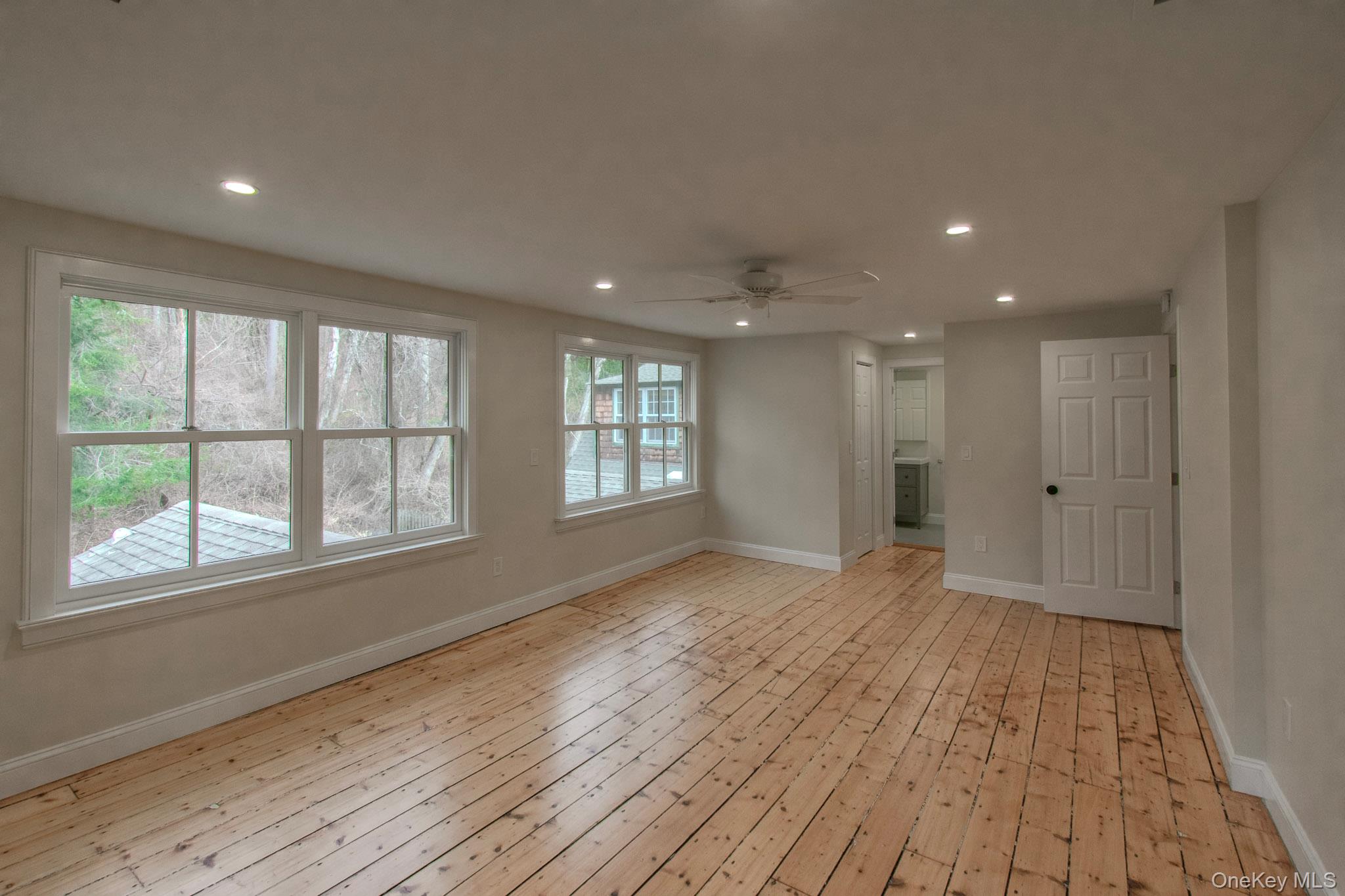 54 East Lake Stable Road Tuxedo Park, NY 10987 - Photo 20 of 31 Unfurnished living room featuring ceiling fan, a wealth of natural light, and light hardwood / wood-style flooring