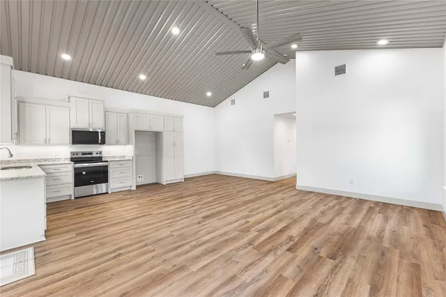 a large room with stainless steel appliances wooden floors and large window