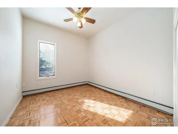 an empty room with a window and ceiling fan