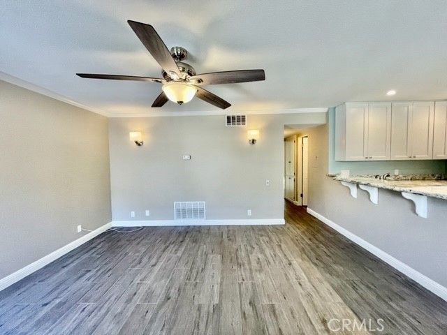 a view of an empty room with wooden floor and a ceiling fan
