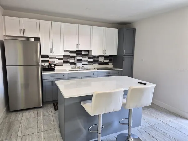a kitchen with a refrigerator a stove a sink and white cabinets
